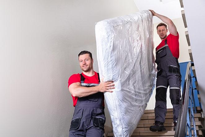 heavy lifting as a box spring is carried away for disposal in Marmaduke